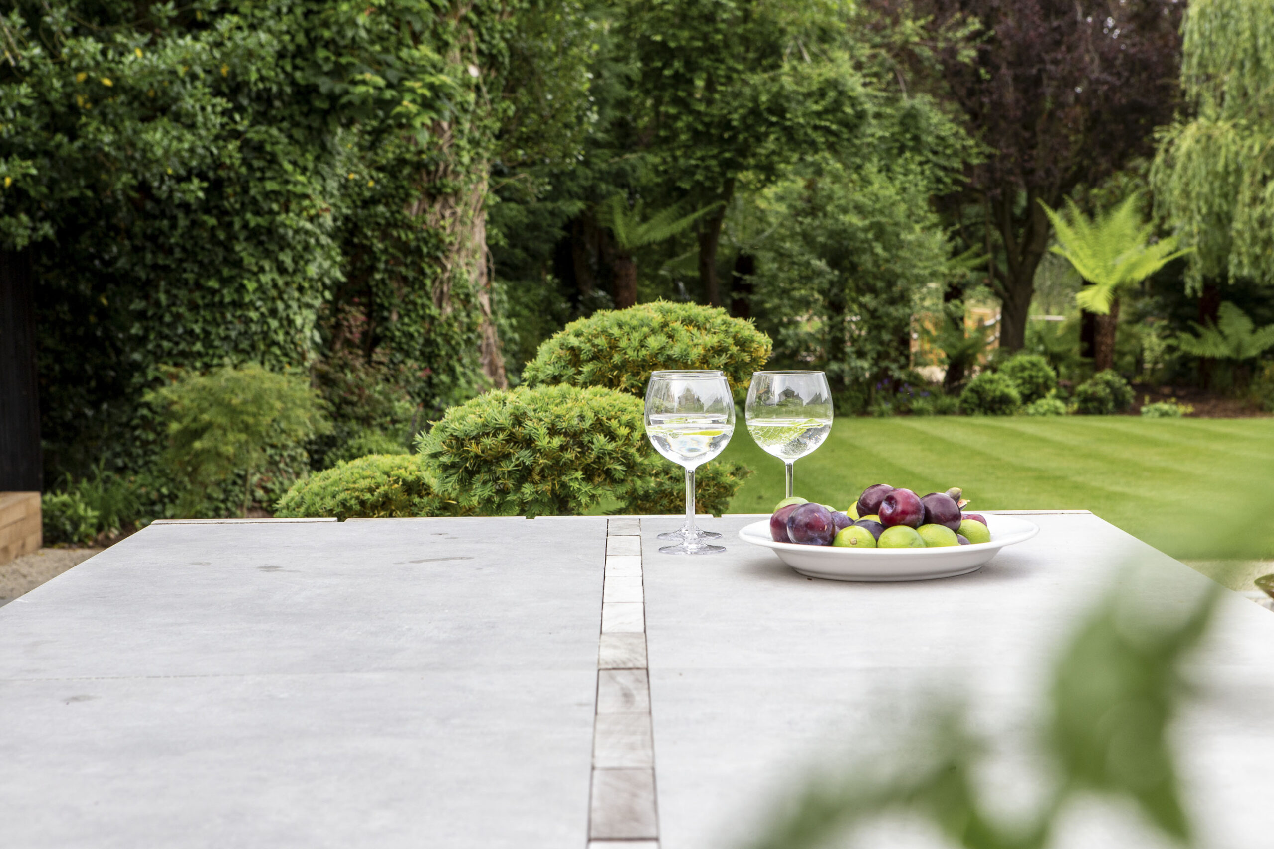 Stone outdoor kitchen table overlooking lawns landscaping design