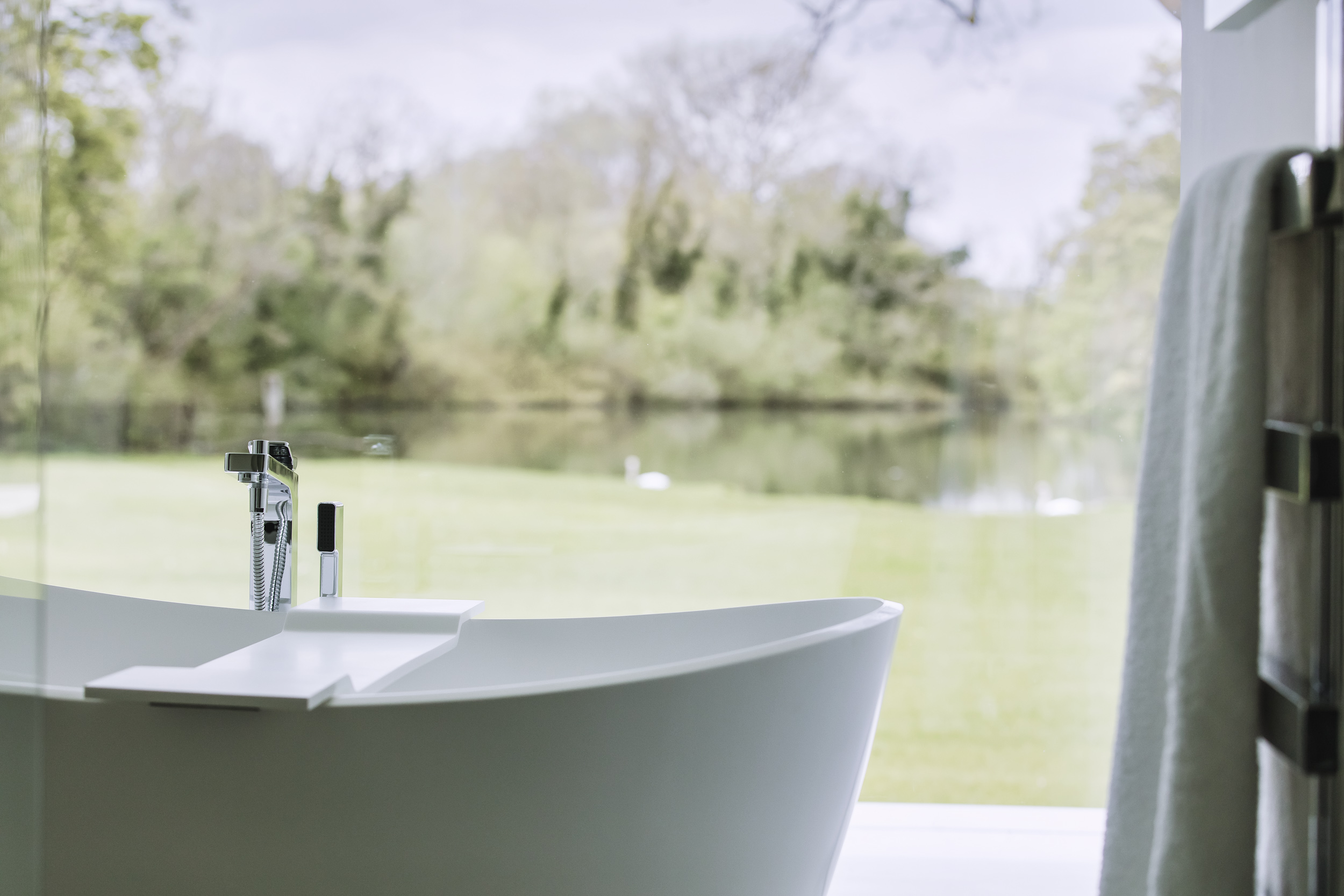Frameless glass wall to luxury bathroom design overlooking countryside views